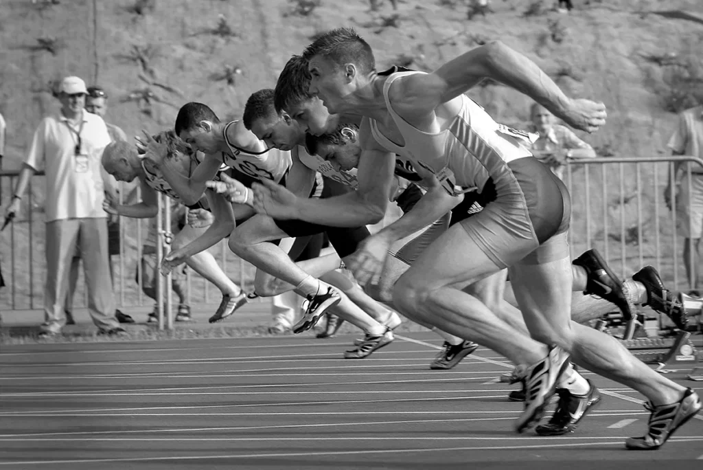 Sprinters launching from the starting blocks at the beginning of a track race, symbolising competition and the importance of a strong start.